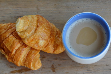 butter croissant and milk coffee on wooden board