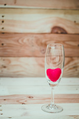 red heart inside wine glass on wood background, loving drink wine concept.