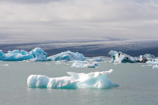Melting glaciers climate change concept. Dramatic image of icebergs in Jokulsarlon lagoon. South Iceland. Amazing travel destination. Vatnajokull glacier on the background.