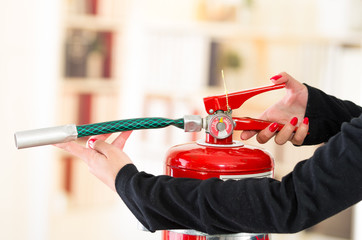 Closeup woman hands with red nailpolish showing how to operate fire extinguisher