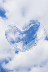 Heart-shaped bubble against cloudy sky background.