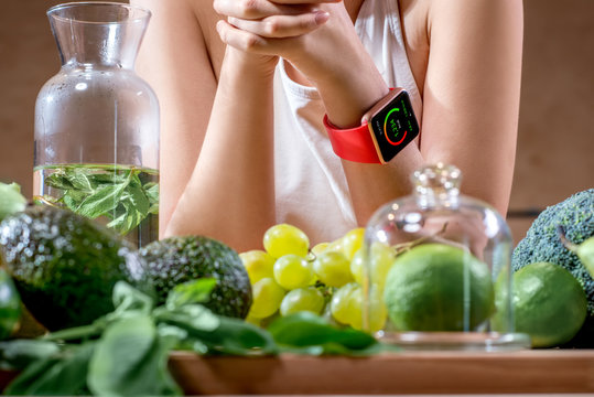 Female Hands With Smart Watch Showing Calories And Green Fruits On The Foreground