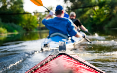 rowers on canoe floating to shore - obrazy, fototapety, plakaty