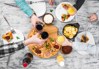 people clanging glasses together having pizza