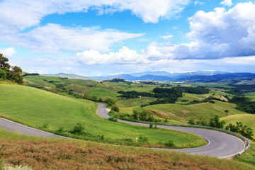 Fototapeta na wymiar Road rural landscape of Tuscany and green rolling hills near Vol