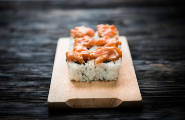 a set of sushi rolls with salmon topping on wooden board