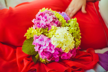 Bunch of flowers next to the pregnant in the red dress