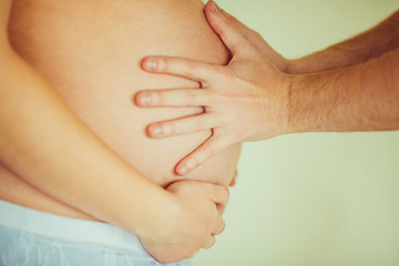 Man touchs with two hands belly of woman