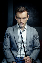 Portrait of Young handsome man in blue suit smoking hookah with weathered brick wall on background
