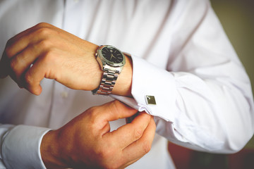 Close-up of hand groom buttoning cuffs his hands and cufflink on his suit. Instagram colors toning