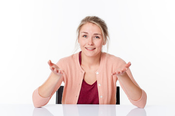 serene smile - smiling young blond woman sitting, showing both empty hands to hold something, white background studio.
