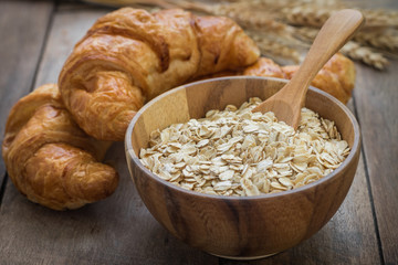 Oat flakes in wooden bowl and croissants
