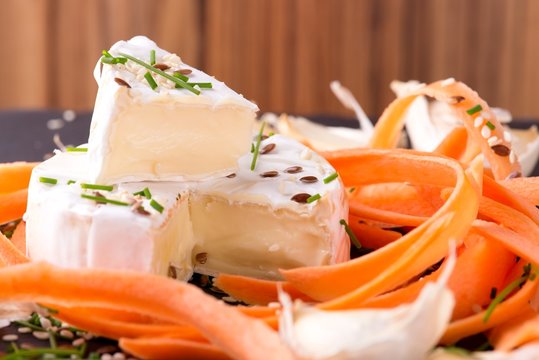 Portion of white camembert with carrot and chive