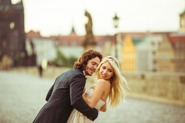 Fototapeta premium Romantic newlywed couple on honeymoon, hugging on bridge in Prag