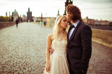 Naklejka premium Romantic newlywed couple on honeymoon, kissing on bridge in Prag
