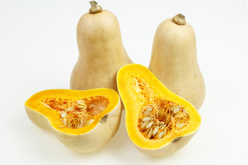 Butternut squash fruits, one cut in half, on white background.