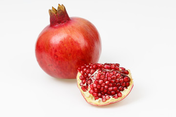 Fresh red pomegranate fruit, with one peeled piece, on white background.