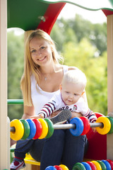 Fototapeta na wymiar Happy mother with two year old son on the playground