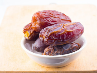 sweet dry date palm fruit on white dish on wood