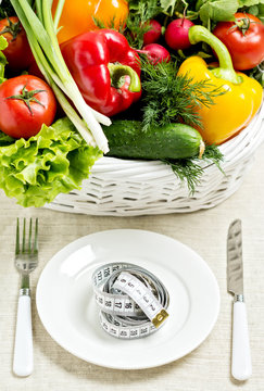 Concept of a healthy diet. The basket of vegetables and a plate