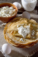 Pancakes heap, sour cream, milk on a wooden table. Traditional R
