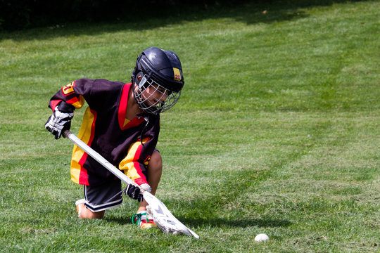 Little boy playing in protective gear lacrosse in the park