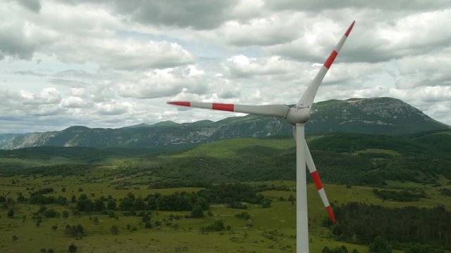 200% speed up flight around wind turbine with beautiful time lapse clouds silhouette on landscape and mountain range at background.
