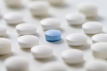 White pills  with ablue one  in the middle on  white backgroung