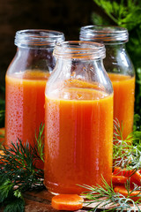 Freshly squeezed juice of carrots in glass bottles, vintage wood