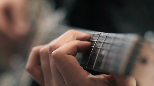 close up of hands playing a guitar
