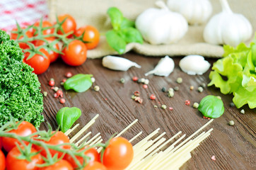 Tomatoes, spaghetti, parsley and garlic on wooden table