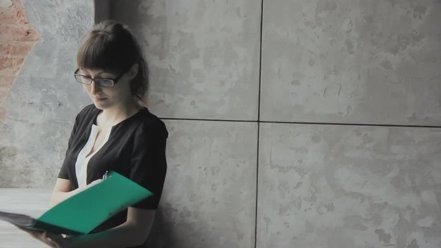 Business girl with green folder in hand writes HD