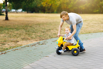 Young pregnant mother resting with her son in summer park and bl