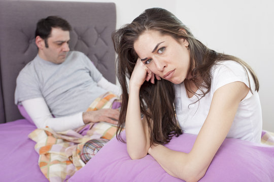 Angry woman sitting in bed, couple is fighting because he's working too much