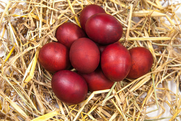 Easter eggs in a straw nest on rustic wooden background. Happy E