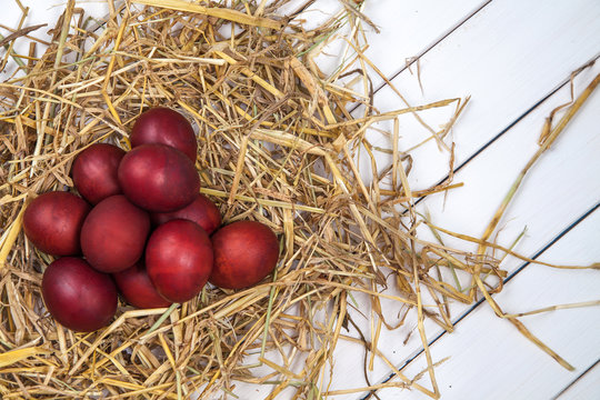 Easter eggs in a straw nest on rustic wooden background. Happy E
