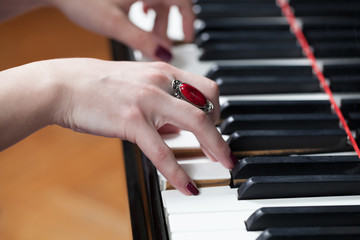A woman with red ring playing piano