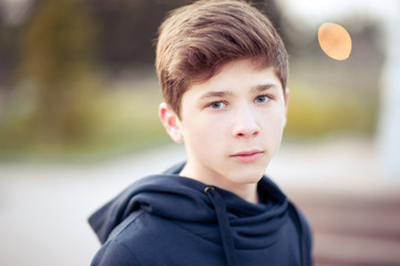 Handsome teenage boy 14-16 year old outdoors closeup. Looking at camera. Teenager hood.