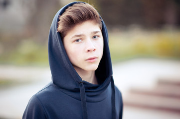 Stylish blond teen boy wearing hoodie outdoors. Looking at camera. Teenager hood. 