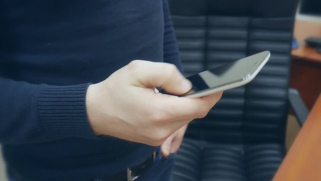 Male  hands playing game on smartphone in the office.  