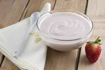 Closeup of delicious strawberry yogurt on wooden table. High nutritional value