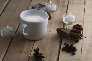 cup of steaming milk on old wooden boards, the board is chocolate, cinnamon, raisins