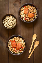 Traditional Chilean dish called Porotos con Riendas (English: beans with reins), made of cooked beans, linguine (flat spaghetti) and served with fried sausage, photographed on wood with natural light