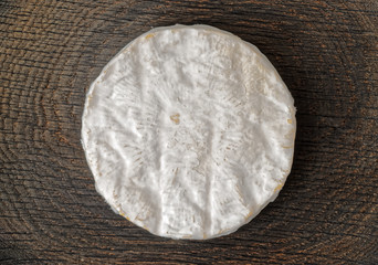 Piece of brie cheese on wooden surface - obrazy, fototapety, plakaty