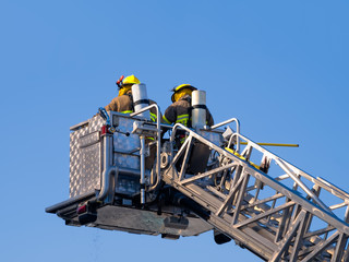 Firefighters on platform isolated on blue sky