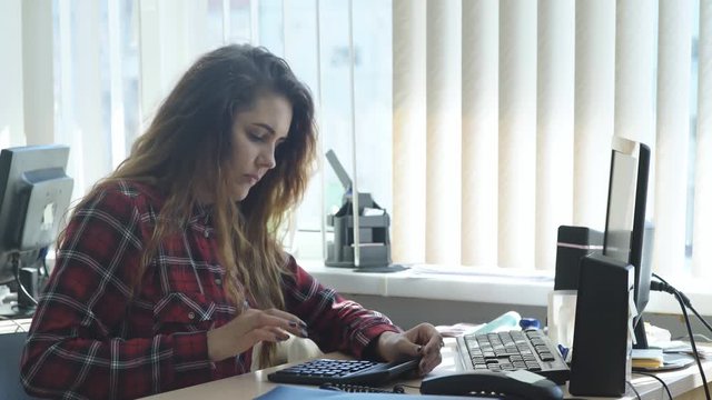beautiful girl works in the office and uses the calculator