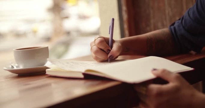 Close up of a Woman Writing Journal in Coffee Shop