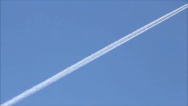 Airplane with contrail in the blue sky 
