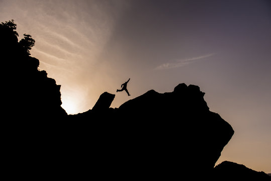 zirve kayalıklarında atlayan maceracı dağcı