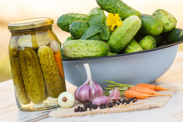 Cucumbers in metal bowl, vegetables and spices for pickling and jar pickled cucumbers